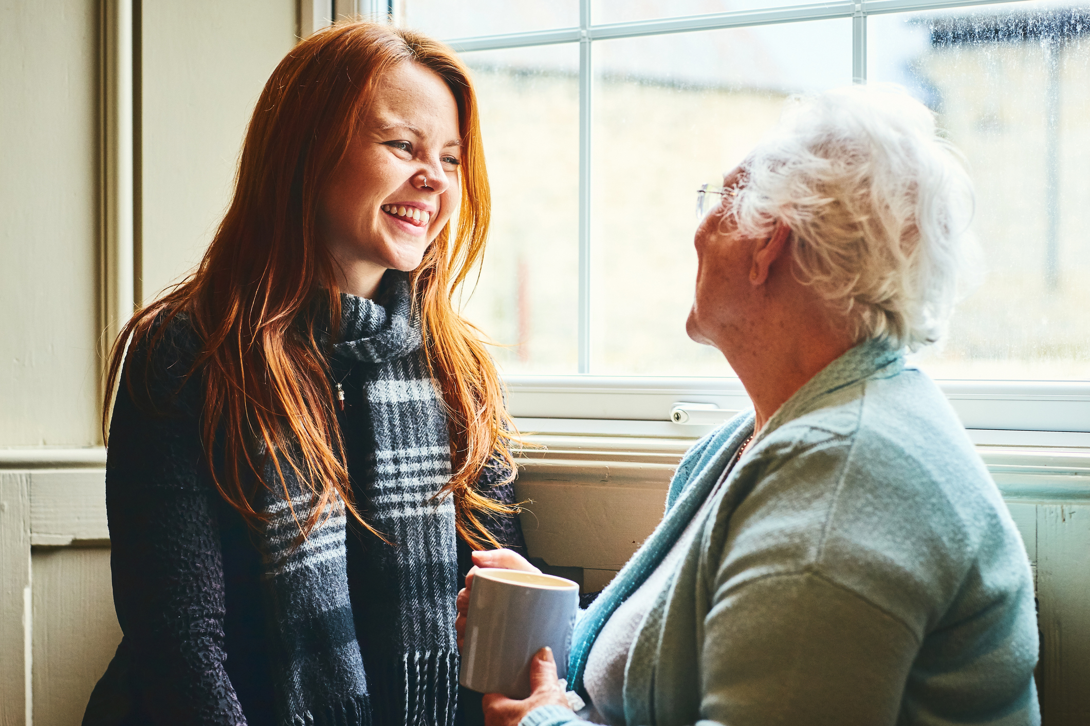 Young caregiver talks with senior woman about in-home care solutions