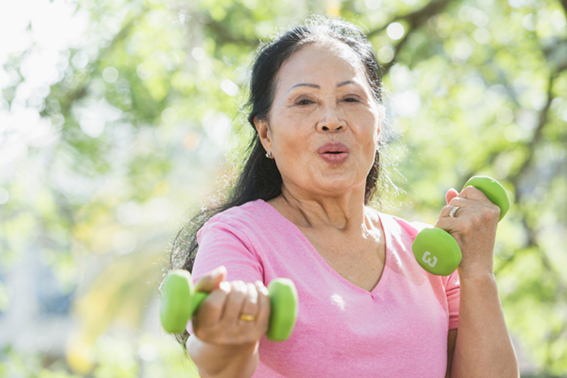An older woman lifts hand weights while exercising to reduce the risk of a stroke.
