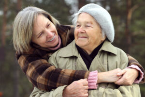 A woman embraces her elderly mother during National Family Caregivers Month, a great time for celebrating family caregivers.